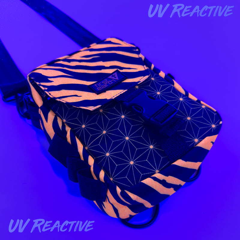 First Earth Sacred Stripes UV-reactive sling bag glowing orange under blacklight for rave and festival gear