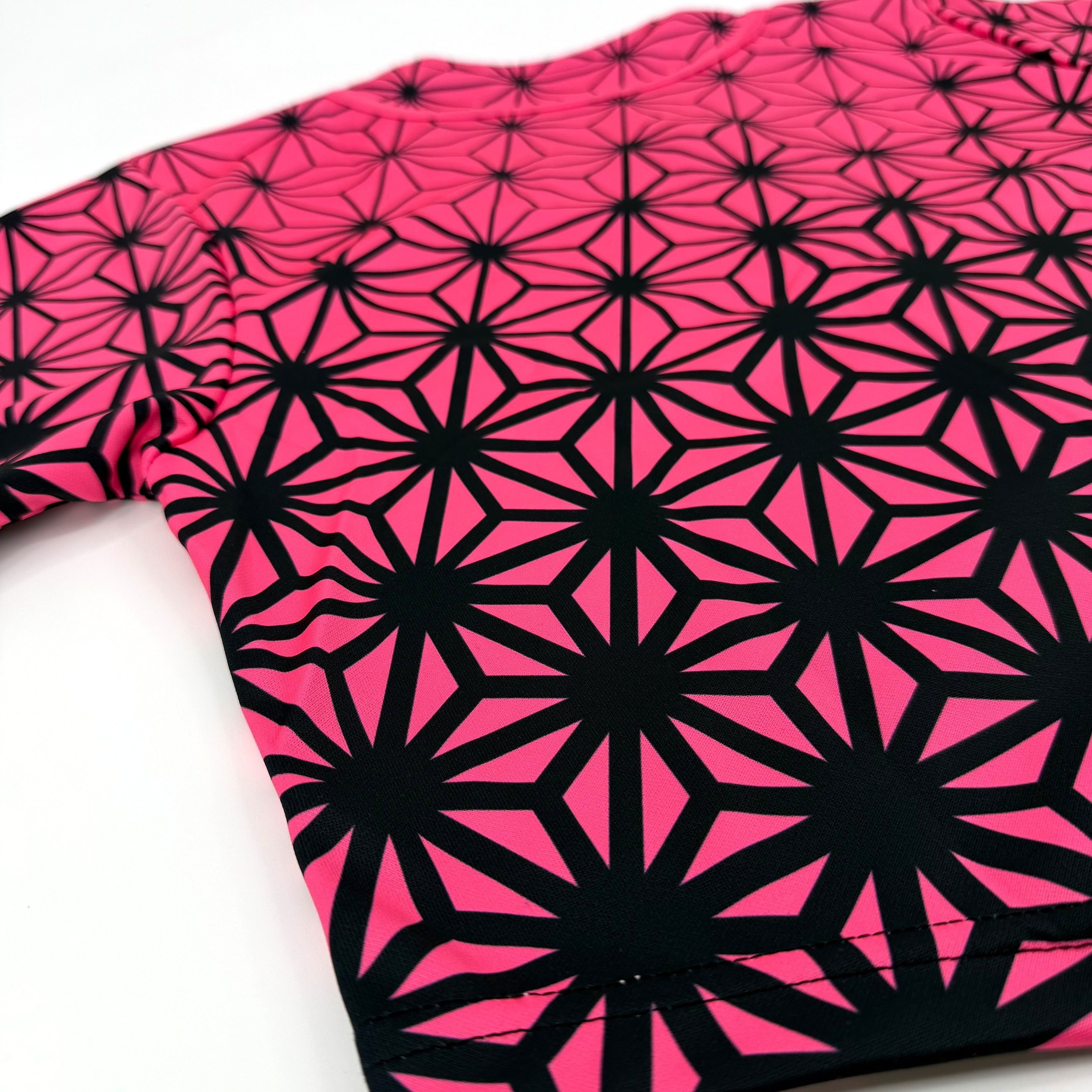 Asanoha pink UV crop baseball jersey by First Earth – cropped rave tee that glows under blacklight, featuring delicate Asanoha geometry on breathable fabric 