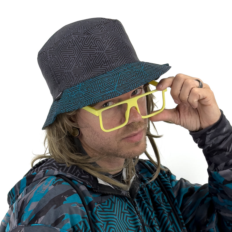 First Earth Shadow reversible bucket hat on model with dark grey geometric maze pattern and teal-trimmed brim