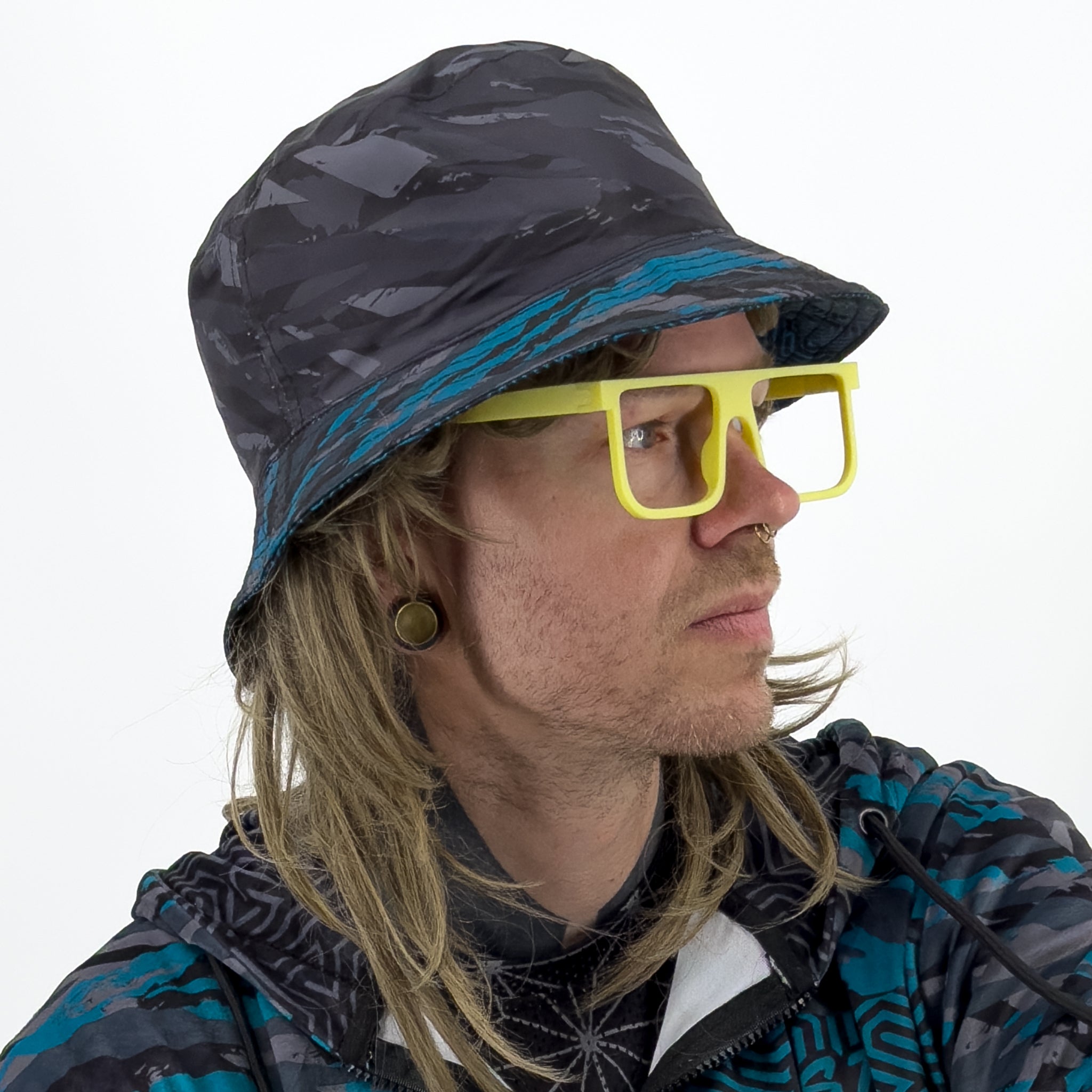 First Earth Shadow reversible bucket hat side view on model showing fractured grey black pattern with teal striped edge