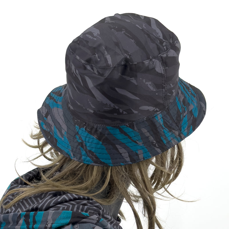 First Earth Shadow reversible bucket hat back view showing fractured grey black pattern and teal striped brim underside