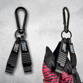 Two black First Earth Flow Star carabiner clips on a concrete background, the right one clipped to a folded red and black Flow Star