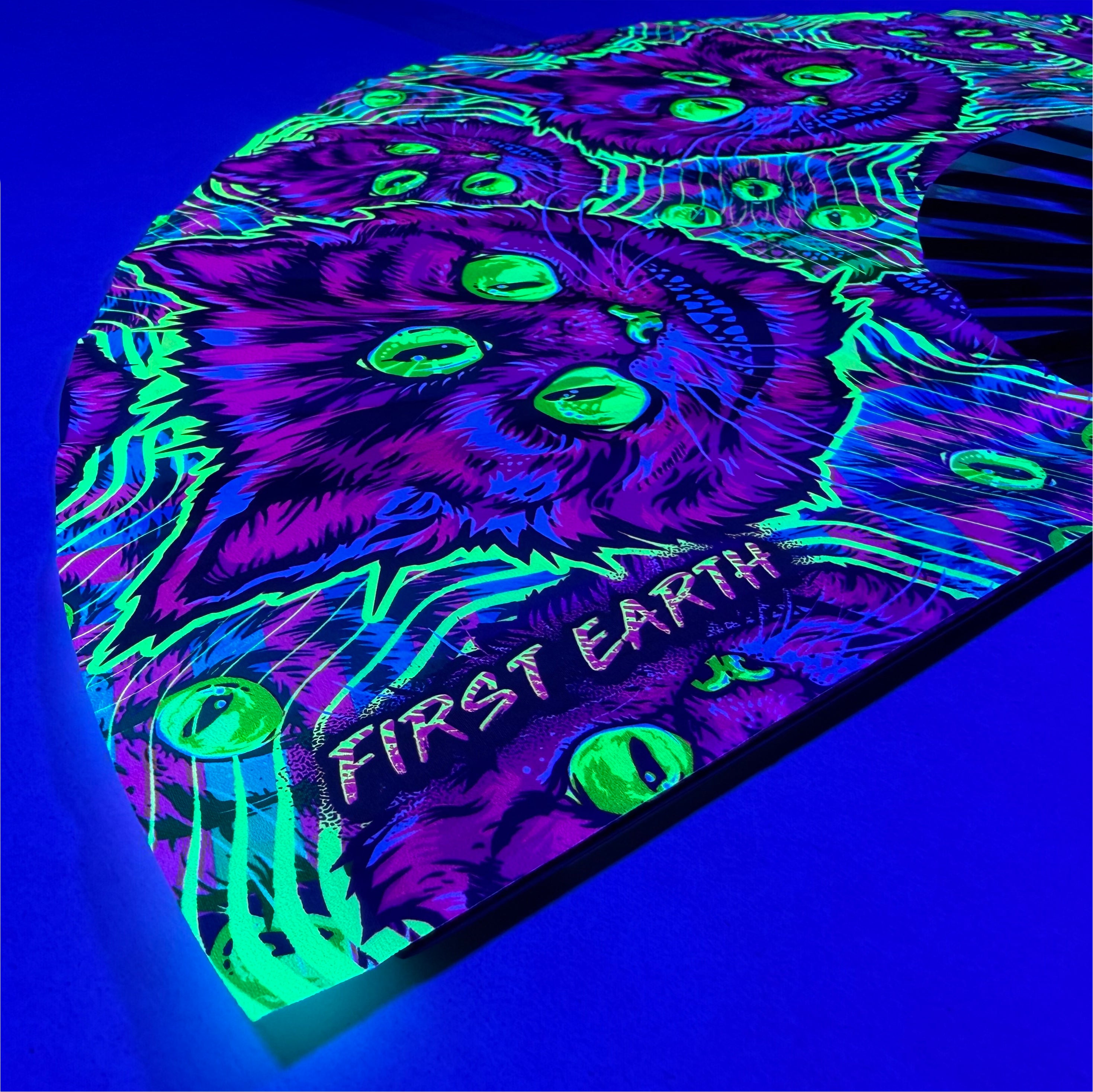 Cheshire Cat UV glow hand fan by First Earth – collapsible rave fan with glowing Cheshire Cat design, bamboo ribs, and vibrant polyester fabric for festival breeze