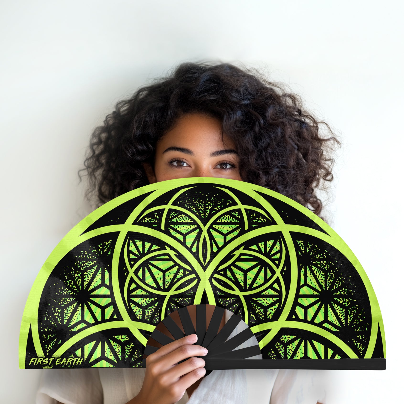 Flower of Life UV glow hand fan green by First Earth – folding rave fan with sacred geometry glowing under blacklight, bamboo handle, vibrant polyester fabric