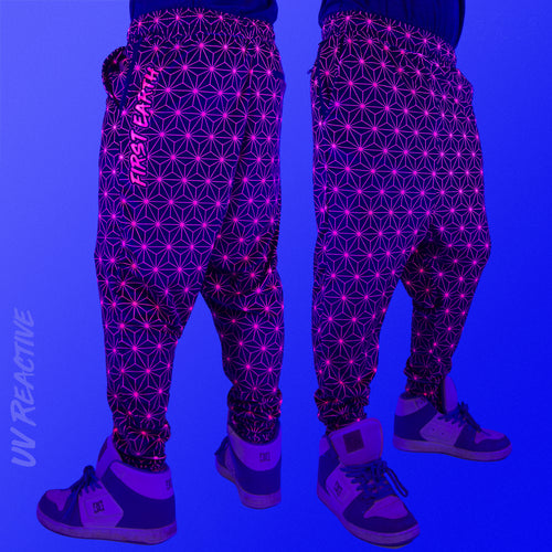 First Earth Asanoha Pink velvet harem joggers under UV blacklight on model showing glowing pink geometric asanoha pattern
