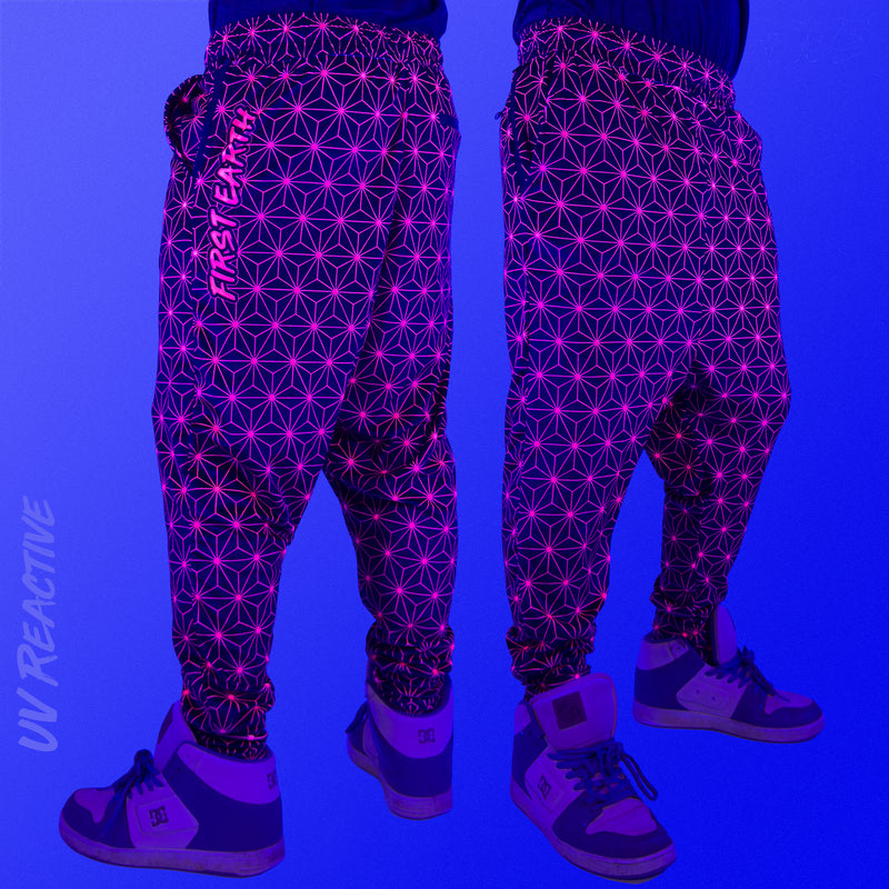 First Earth Asanoha Pink velvet harem joggers under UV blacklight on model showing glowing pink geometric asanoha pattern