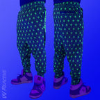 First Earth Asanoha Yellow velvet harem joggers under UV blacklight on model showing glowing yellow geometric asanoha pattern