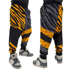 First Earth Sacred Stripes velvet harem joggers on model showing front and back views with orange tiger stripes and geometric panels