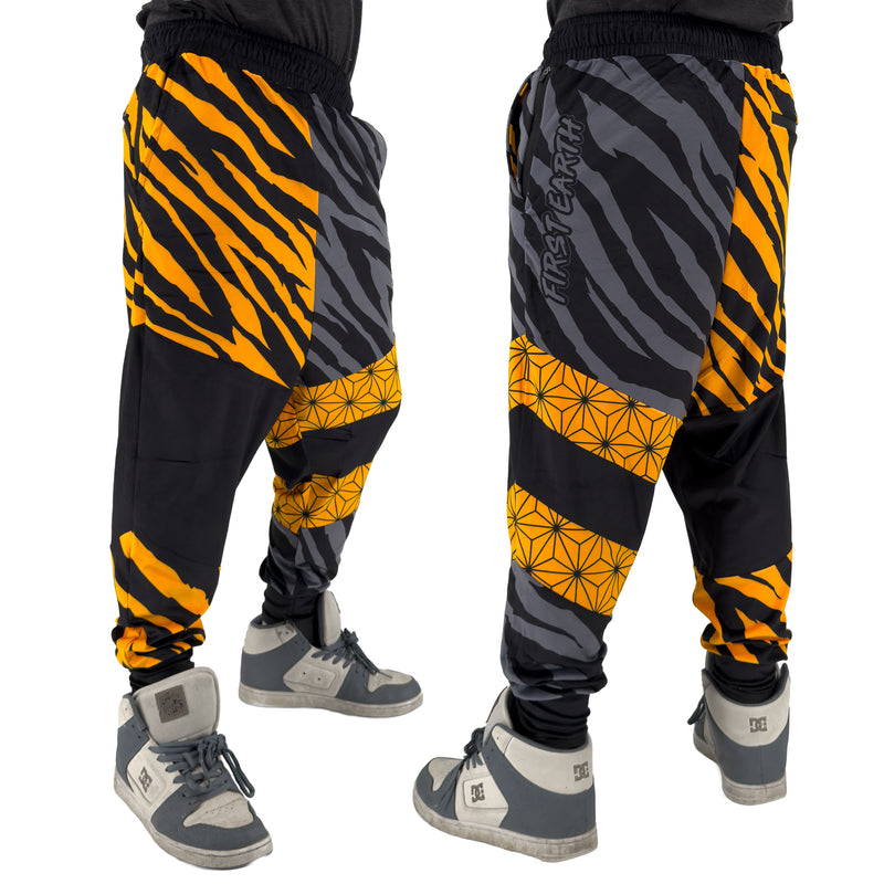 First Earth Sacred Stripes velvet harem joggers on model showing front and back views with orange tiger stripes and geometric panels