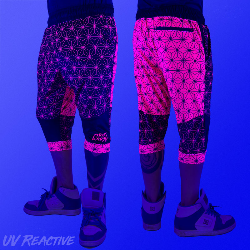 First Earth Asanoha Pink 3/4 velvet harem shorts under UV blacklight on model, showing front and back glowing pink pattern
