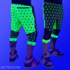First Earth Asanoha Yellow 3/4 velvet harem shorts under UV blacklight on model, showing front and back glowing yellow pattern