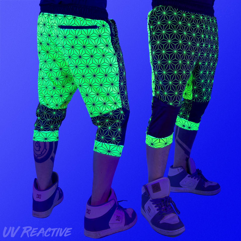 First Earth Asanoha Yellow 3/4 velvet harem shorts under UV blacklight on model, showing front and back glowing yellow pattern
