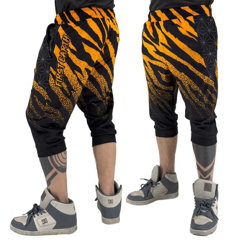 First Earth Sacred Stripes three-quarter velvet harem shorts on model, showing front and back views with orange tiger stripes and geometric panels