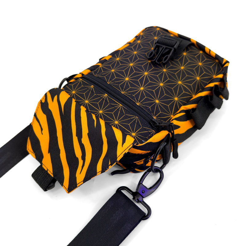 First Earth Sacred Stripes sling bag front with open flap, zipper pocket, buckle, and black strap hardware