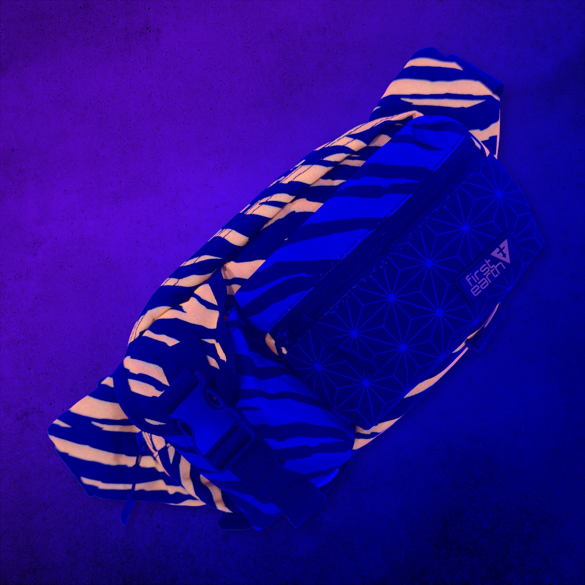First Earth Sacred Stripes crossbody bag front glowing orange under UV black light