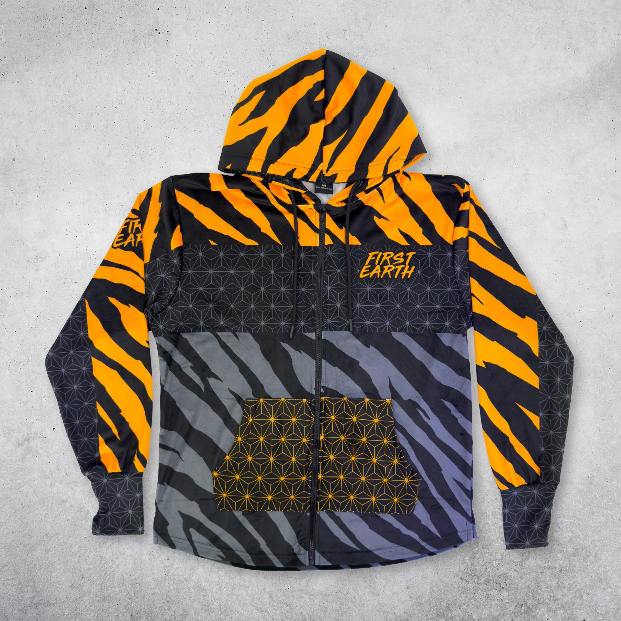 First Earth Sacred Stripes velvet hoodie front with bold orange and black tiger stripes, geometric panel details, zipper, hood, and front pocket